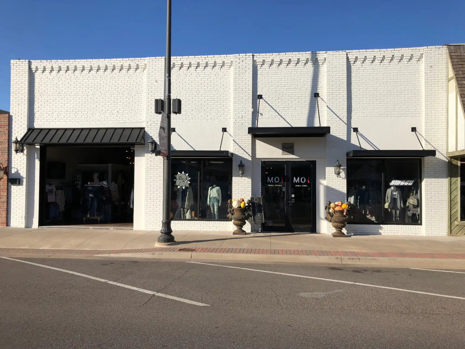 A white brick storefront with black awnings and display windows.